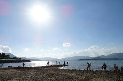 People enjoying at beach during sunny day