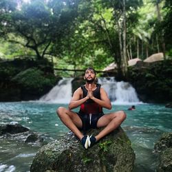 Full length of young man sitting on rock