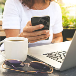 Midsection of woman using phone on table