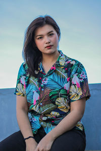 Portrait of beautiful woman sitting against sky