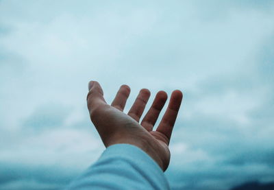 Cropped hand of person gesturing against sky