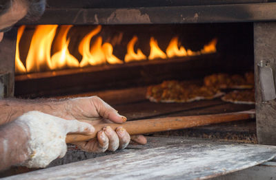 Cropped hand of chef putting pizza in oven