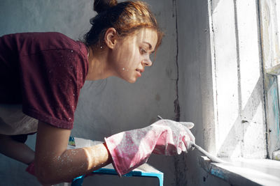 Young woman looking through window