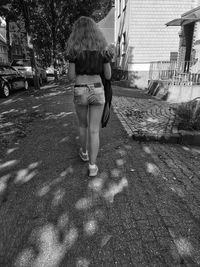 Rear view of boy walking on street in city