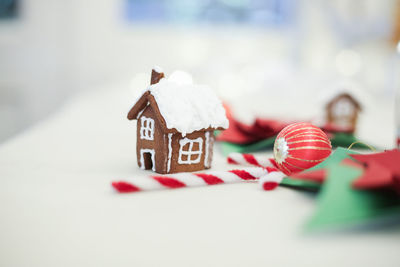 Close-up of gingerbread house and white mugs decorated on table during christmas