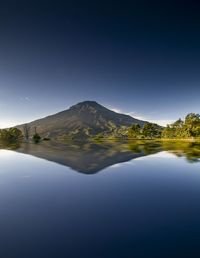 Scenic view of lake and mountains against clear blue sky