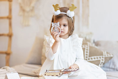 A girl  with a headband  of deer horns and a christmas toy in her hands.christmas holidays