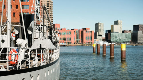 Boats moored at harbor in city against clear sky