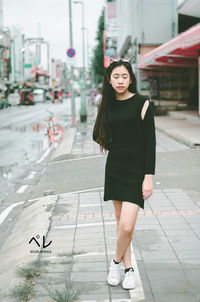 Young woman standing on footpath in city