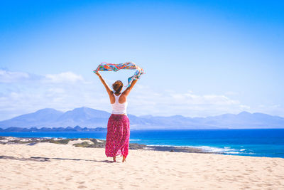 Rear view of woman standing at sea against sky