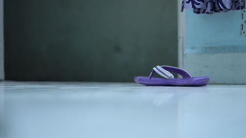 Close-up of shoes on purple floor against wall