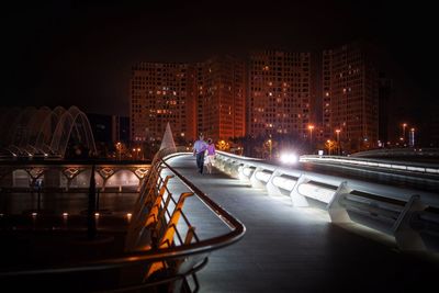 Couple walking on bridge in city at night