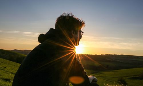 Woman on hill against sky during sunset