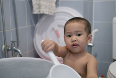 Cute boy holding mug in bathroom