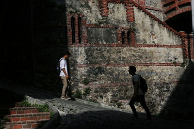 Rear view of people walking on old building