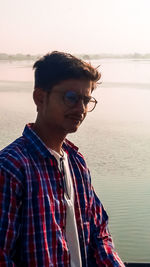 Young man looking at sea against sky