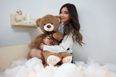 Portrait of a smiling young woman holding toy at home