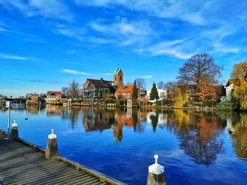 Buildings by lake against blue sky