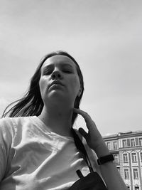 Portrait of young woman looking away against sky