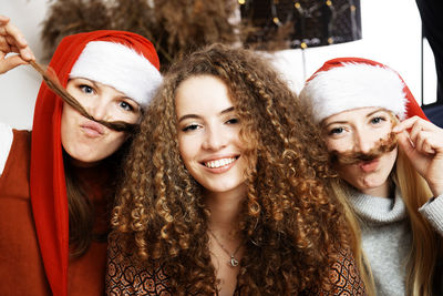 Three young attractive women in santa hats celebrate christmas at home