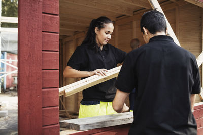 Male and female carpentry students working at wooden cabin