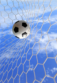 Soccer ball hitting in goal post against blue sky