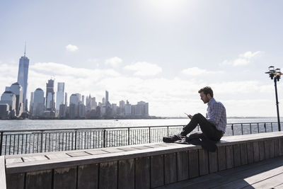 Usa, man using tablet at new jersey waterfront with view to manhattan