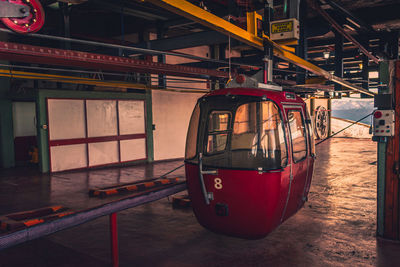 Red cable car waiting for passengers to go to the top of snowy mountains seen in the background