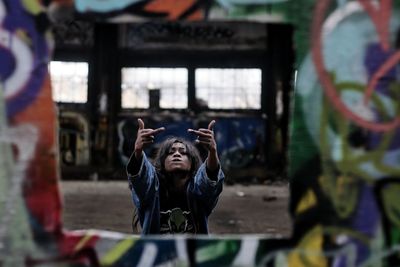 Portrait of young woman showing middle finger seen through window