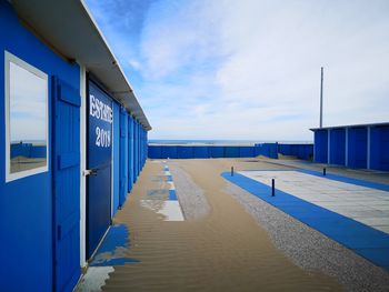 Walkway by sea against blue sky