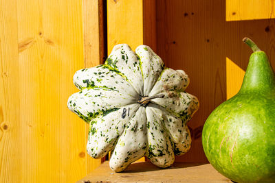 Close-up of pumpkins on table against wall