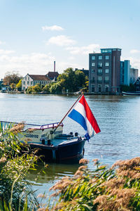 Sailboats moored on river by buildings in city against sky