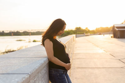 Side view of woman standing in city against sky