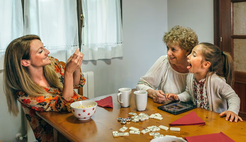 Close-up of smiling woman photographing family at table