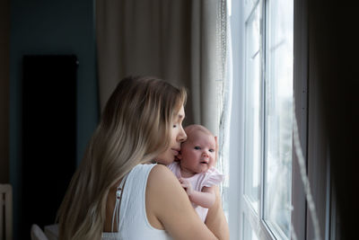 Side view of girl looking through window