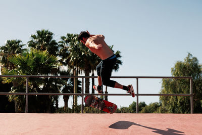 Low angle view of young woman standing by railing