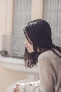 Side view of young woman sitting at home