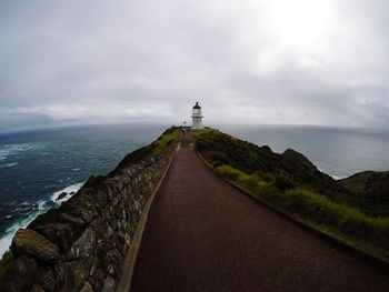 Lighthouse amidst sea and buildings against sky