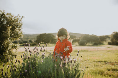 Cute girl standing on field against sky