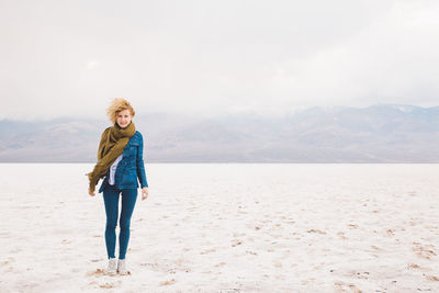 Portrait of young woman standing at death valley national park against cloudy sky