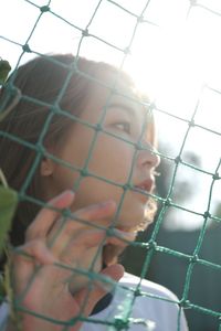 Portrait of woman seen through chainlink fence