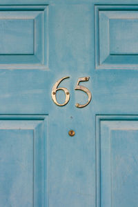 House number 65 on a light blue wooden front door in london 