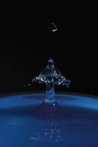 Close-up of drop falling on glass against black background