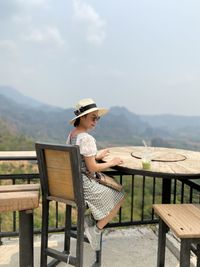 Women sitting on bench at table against mountains