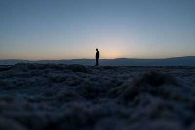 Silhouette man standing on beach against sky during sunset