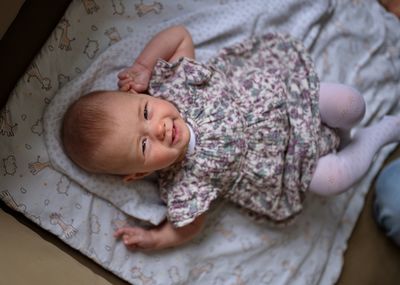 High angle view of little baby girl lying on the sofa