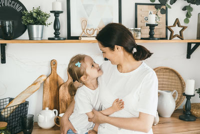 A mother gently hugs her four-year-old daughter.