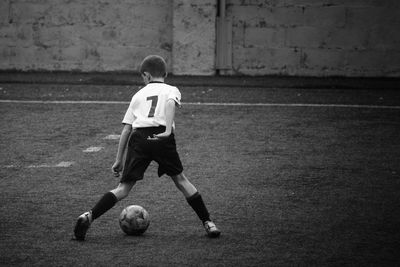 Rear view of boy playing soccer at home
