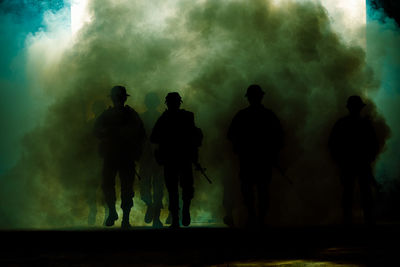 Silhouette group of thai soldiers special forces full team in uniform walking action through smoke 