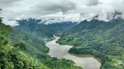 Scenic view of river amidst mountains against cloudy sky